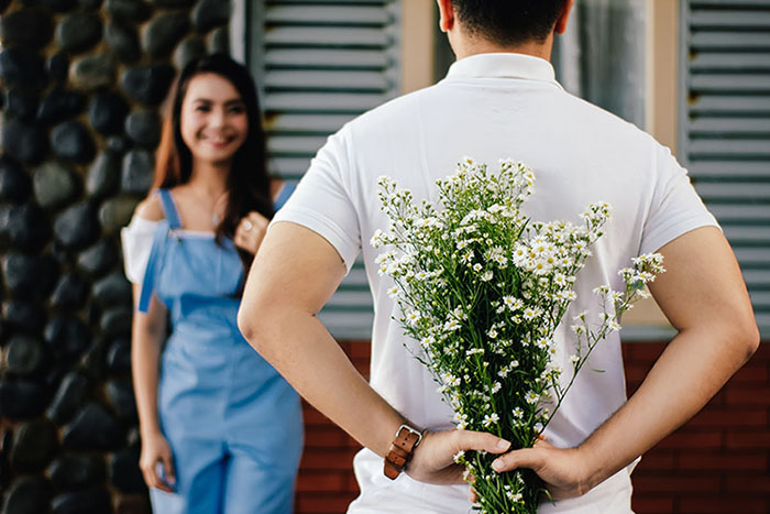 A photo of a guy wearing a white T-shirt and bringing a flower