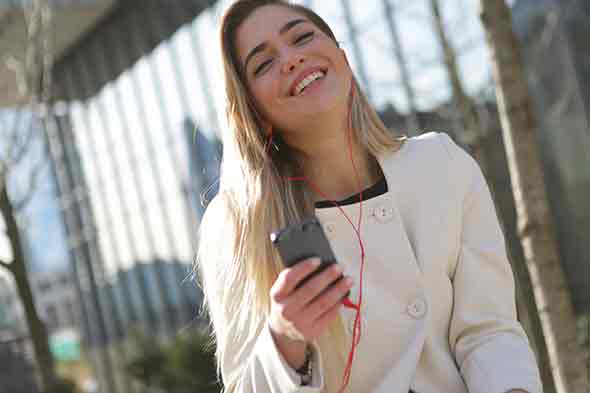 A photo of a woman smiling while holding up her smartphone