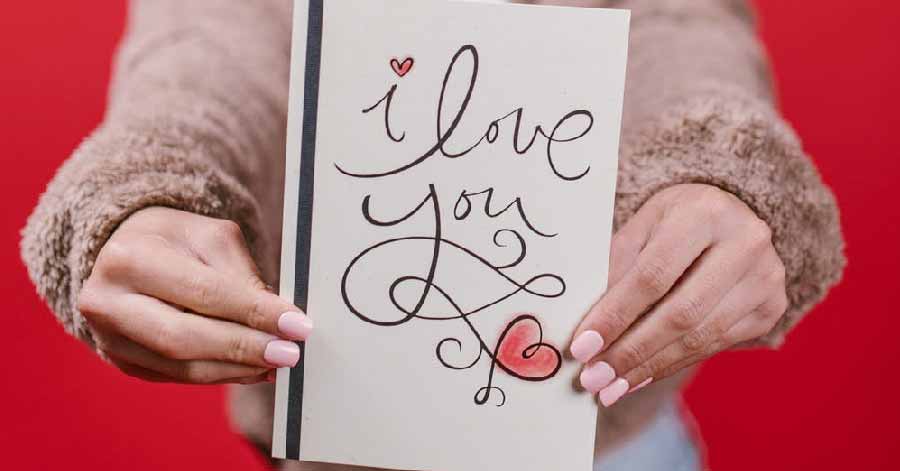  closeup photo of a woman holding a card that says “I love you”