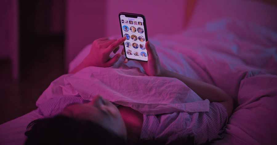 A photo of a woman inside a pink room navigating her phone.