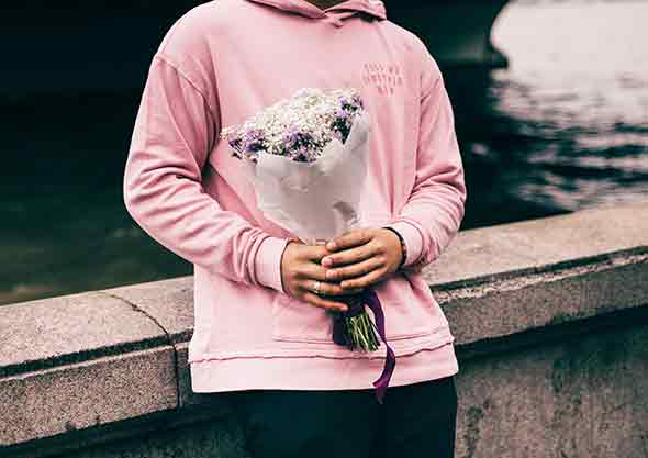  A photo in a man in a pink pullover holding a flower bouquet