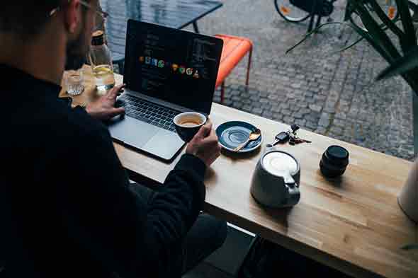 a man holding coffee cup, using a laptop
