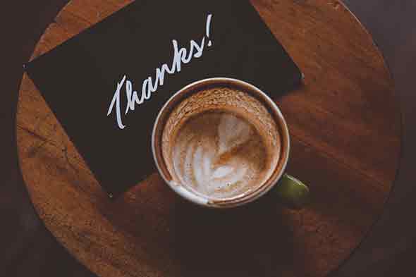  A photo of a cup of coffee and a thank you card on a round table