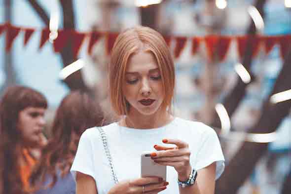A woman in a white shirt looking at her phone