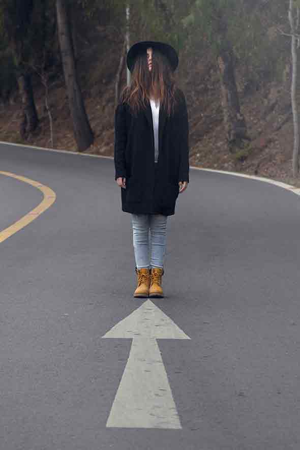 woman with hair covering her face standing in the middle of the road