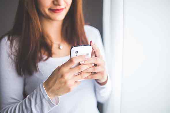 An up close photo of a woman on her phone, slightly smiling