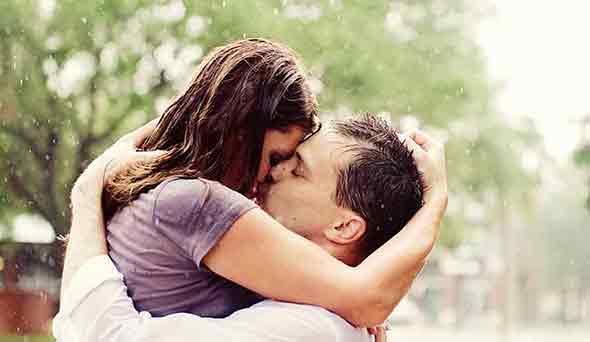  A romantic photo of a couple kissing in the rain.