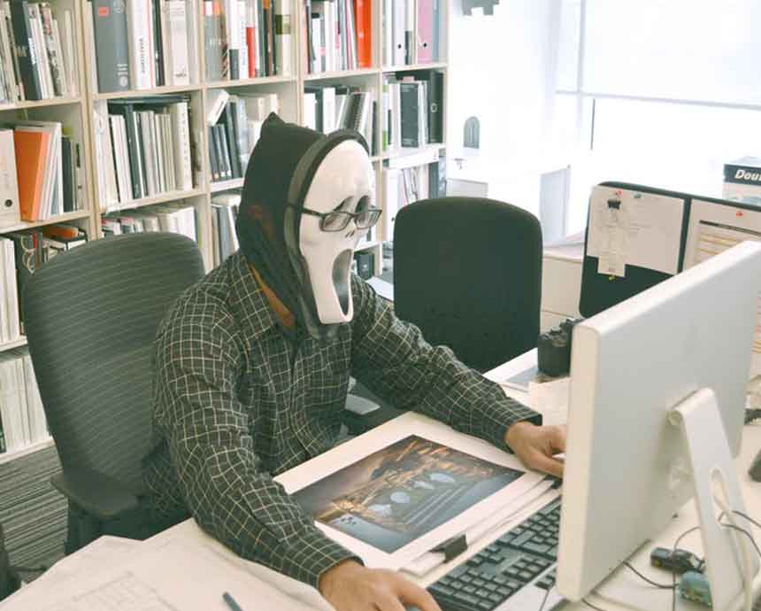 A guy wearing a mask while using the computer.
